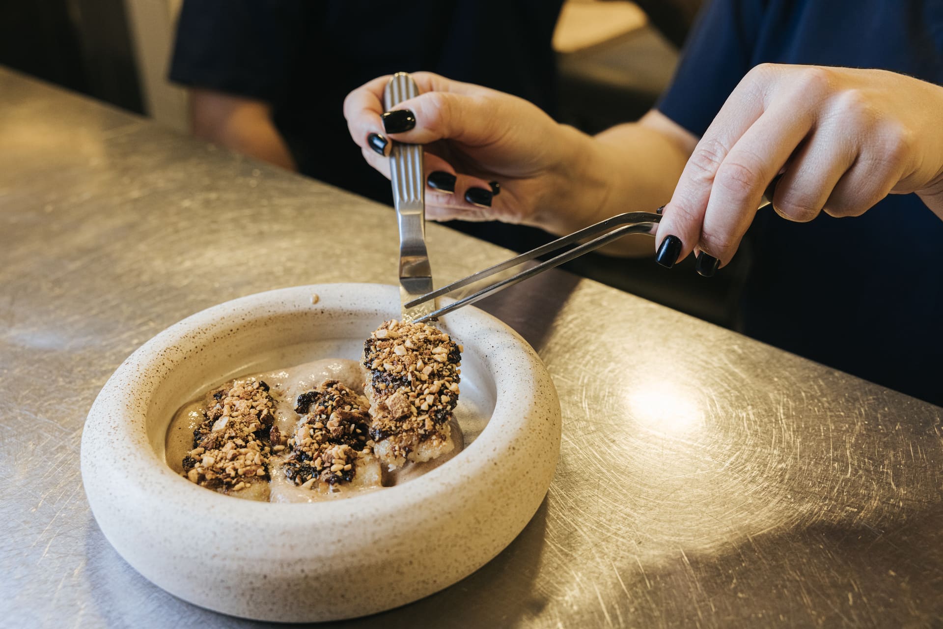 A cook placing a garnish with tweezers