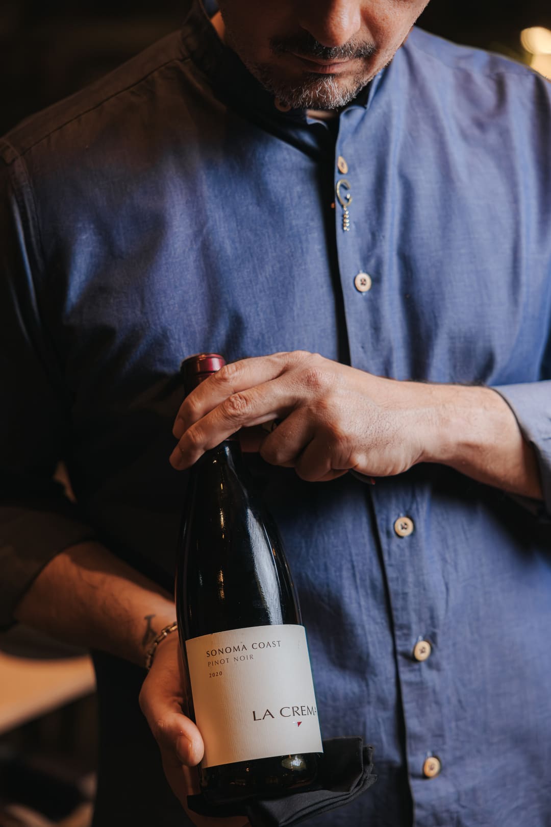 A sommelier presenting a bottle, hands and label in frame