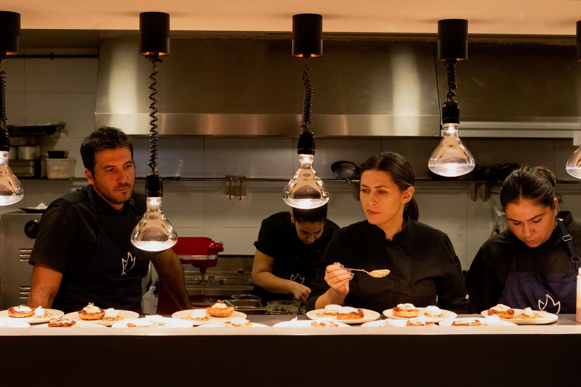 Cooks working side by side along the pass during service